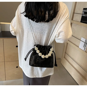 Detail of black drawstring bucket bag with large pearl handle and silver chain strap