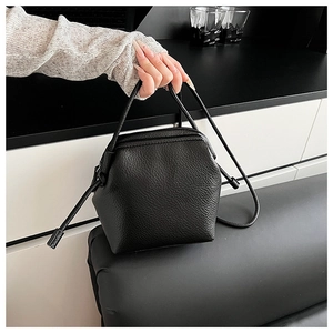 Detail of black lychee texture leather shoulder bag with side knot and slim strap
