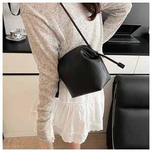 Litchi pattern leather bucket bag shown in a cozy lifestyle setting with crossbody strap