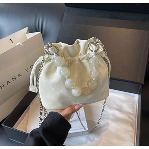 Detail of off-white drawstring bucket bag with marble beads handle and silver chain strap