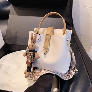 Cream bucket bag with brown handles, wide geometric strap and a cute rabbit charm