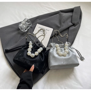 Detail of beaded handle and satin drawstring bucket bags with slim metal chain straps