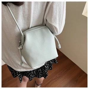 Detail of light mint green pebble leather crossbody bag with adjustable knot strap