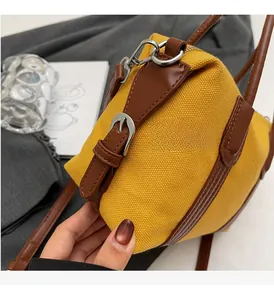 Détail du sac en toile jaune avec sangle en cuir marron et boucle argentée