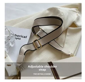 Detail of adjustable wide fabric strap and golden metal buckle on beige crossbody bag