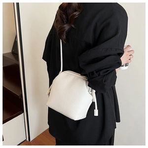 Detailed close-up of white litchi pattern PU leather on a small crossbody bag with strap