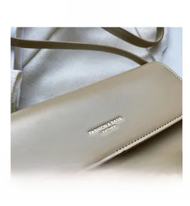Detailed close-up of beige leather handbag flap with gold FASHION & BAGS lettering