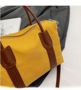Détail du sac Boston en toile jaune avec finitions en cuir marron et fermeture éclair