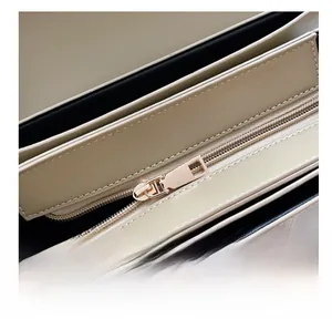 Close-up of smooth gold metal zipper and premium stitching on beige leather bag