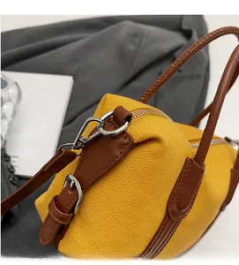 Détails des crochets argentés et des lanières en cuir brun sur un sac boston en toile jaune