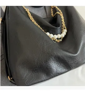 Detail of soft vintage leather tote with elegant gold chain and pearl strap decor
