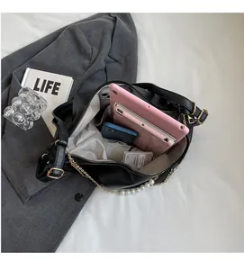 Interior view of large black leather tote bag with pearl chain and diverse daily items