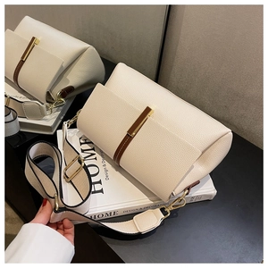 Detail of beige lychee leather crossbody bag with brown trim and stylish wide strap