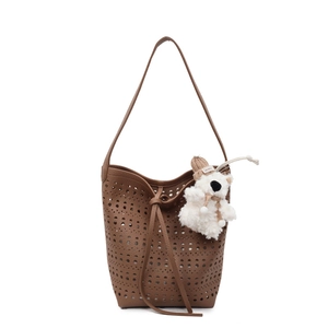 Brown hollow-out bucket bag with laser-cut holes and a cute plush bear charm