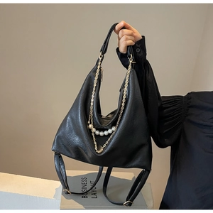 Detail of black faux leather tote featuring gold chains and decorative pearls