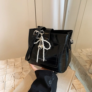 Black crocodile embossed bucket bag with pearl bow and heart charm details