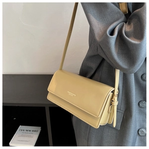 Detail of light yellow smooth leather crossbody baguette bag with fashion logo