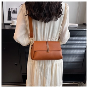 Detail view of brown lychee grain leather crossbody bag with wide woven strap and gold buckle