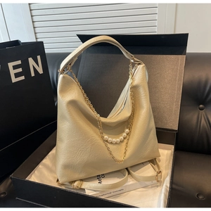 Close-up of cream-colored leather hobo bag with pearl chain in a premium gift box