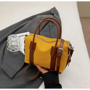 Détail du sac à main en toile jaune avec garniture en cuir brun et fermeture éclair