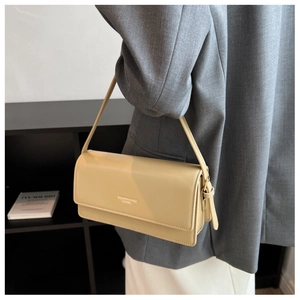 Close-up of khaki faux leather shoulder bag with printed text and side drawstring knots