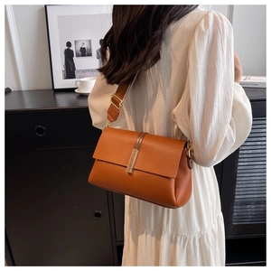 Detail of caramel lychee leather shoulder bag with gold metal buckle and wide strap
