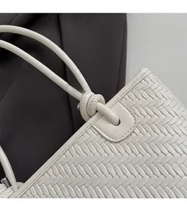 Détail de la texture tressée et de la poignée nouée sur un sac à main beige