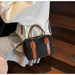 Détail du sac Boston en toile noire et cuir marron porté par un mannequin de mode