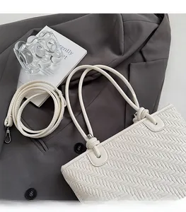 Détail d'un sac cabas tressé blanc avec boucles argentées et bandoulière réglable
