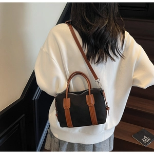 Détail du sac Boston en toile avec poignées en PU marron porté par un mannequin