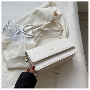Detail of white PU leather bag with embossed lettering on a textured blazer