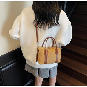Détail du sac Boston vintage en toile moutarde avec lanières et poignées en cuir marron