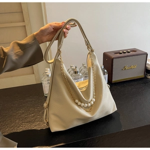Detail of beige faux leather tote bag with vintage pearl and golden chain accessories