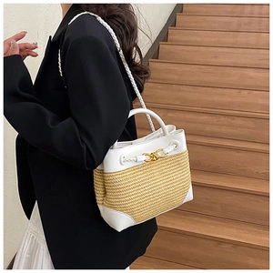 Detail of woven straw shoulder bag with white leather trim and gold knot buckle