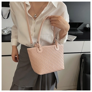 Détail d'un sac cabas tissé rose clair montrant la texture et la bandoulière réglable