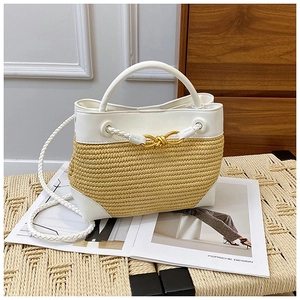 Close-up of woven bucket bag with white leather trim and gold metal knot buckle