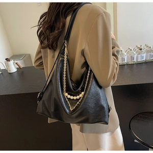 Detail of black Hobo bag with textured PU leather, golden chains, and large pearl accents