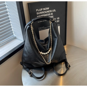 Detail of black textured leather tote with elegant pearl and gold chain strap decoration