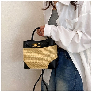 Detail of bicolor straw handbag showing black leather patches and gold twist lock buckle