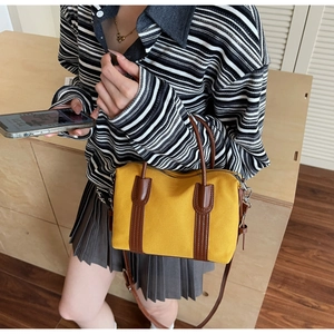 Détail du sac Boston en toile jaune avec finitions cuir porté en bandoulière élégante
