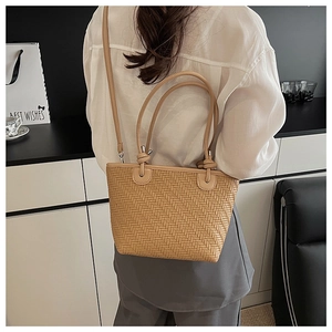 Détail d'un sac cabas tissé marron clair avec motif à chevrons et doubles poignées sur modèle
