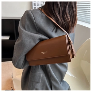 Model wearing dark brown vintage leather shoulder bag with gold fashion lettering