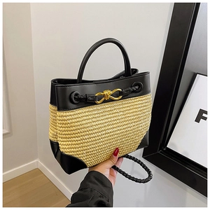 Close-up of woven straw and black leather handbag with a vintage gold metal twist lock