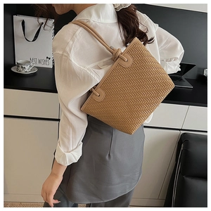 Détail d'un sac bandoulière marron tissé avec texture à chevrons et bandoulière en cuir