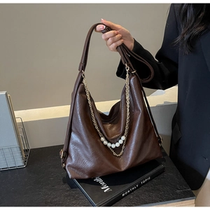 Detailed view of deep brown tote bag with gold chain and large pearl decoration
