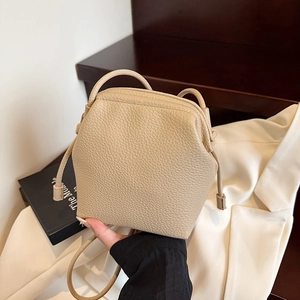 Minimalist beige pebble leather crossbody bag with thin strap and stylish drawstring detail