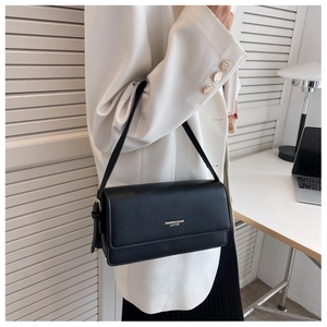 Detail of black leather underarm bag with gold lettering shown in office setting