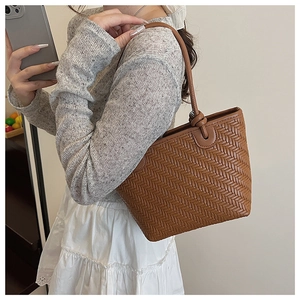 Gros plan détaillé du sac cabas tressé marron avec design de poignée nouée et texture PU