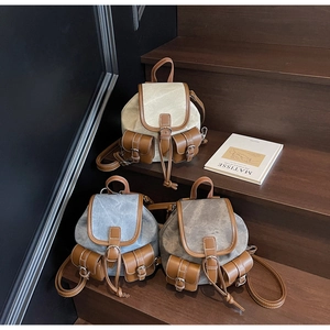 Three vintage denim backpacks with leather trim displayed on wooden stairs