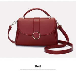 Detailed view of burgundy soft leather bag with elegant golden circular metal buckle